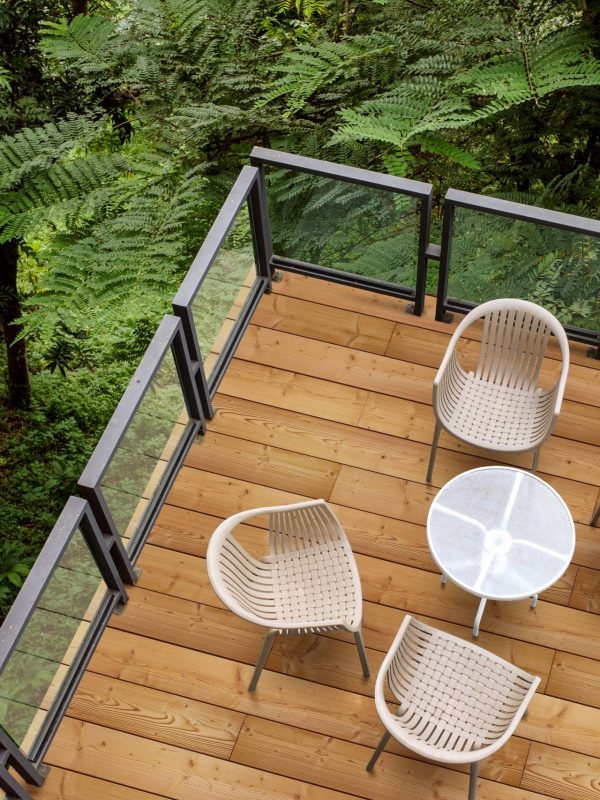 Wooden chairs with glass table on patio in tropical garden